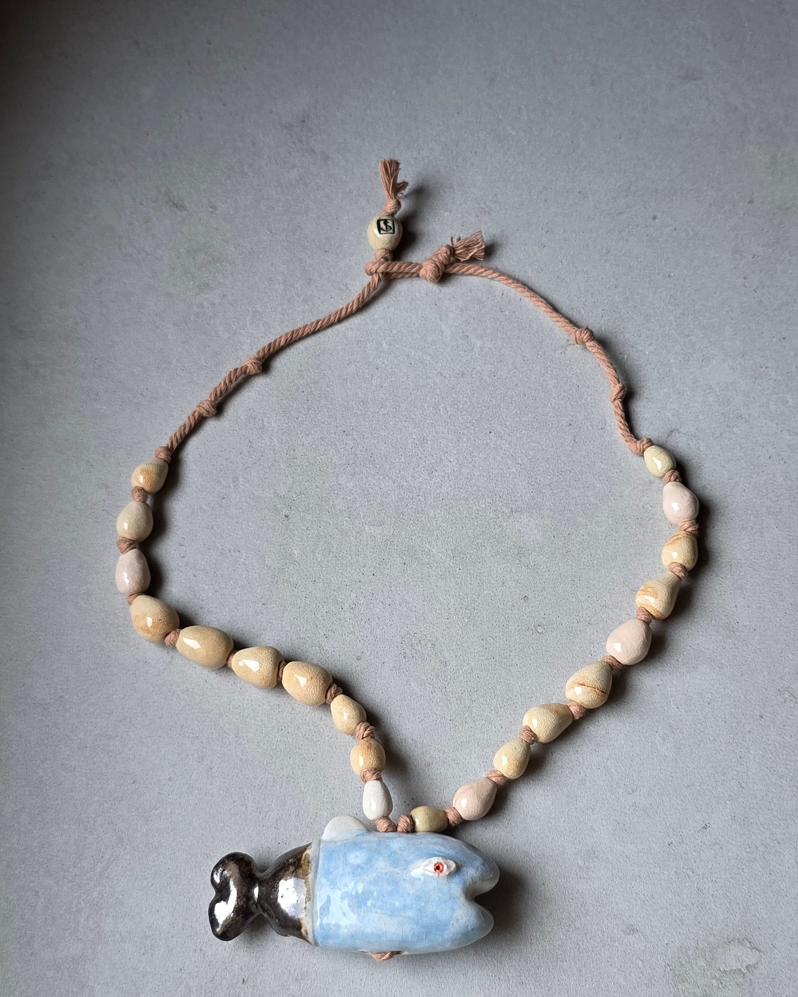 Collana Pesce Azzurro – la collana distesa in lunghezza, con il pesce in basso e la perla avorio SF in alto