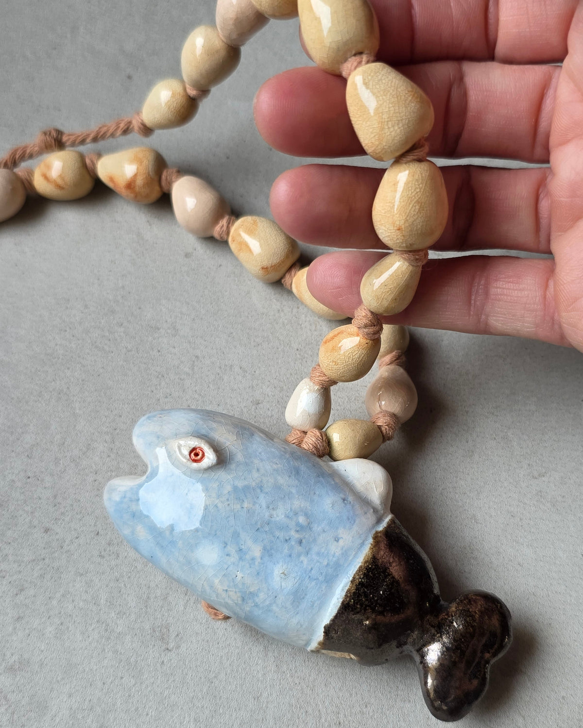 Collana Pesce Azzurro – il pesce sotto le perle tenute in mano, per la scala