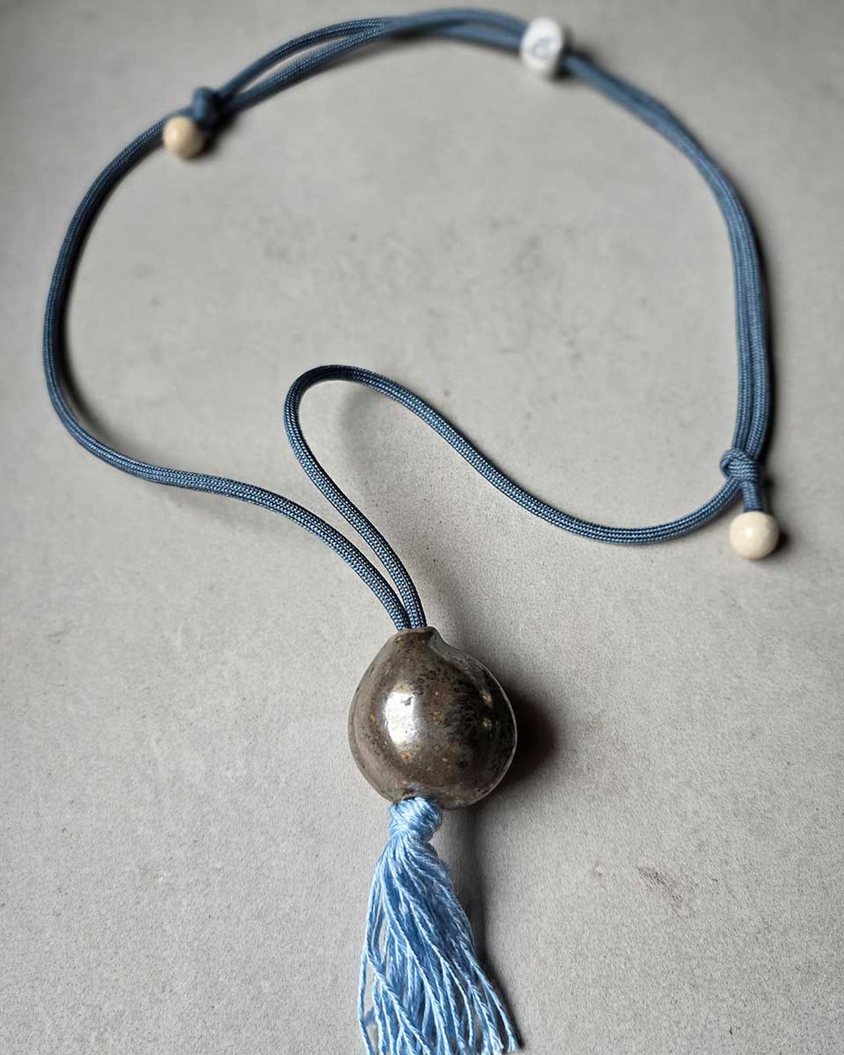 Collana Sacro Om – Oro – piano grigio con i due nodi scorrevoli