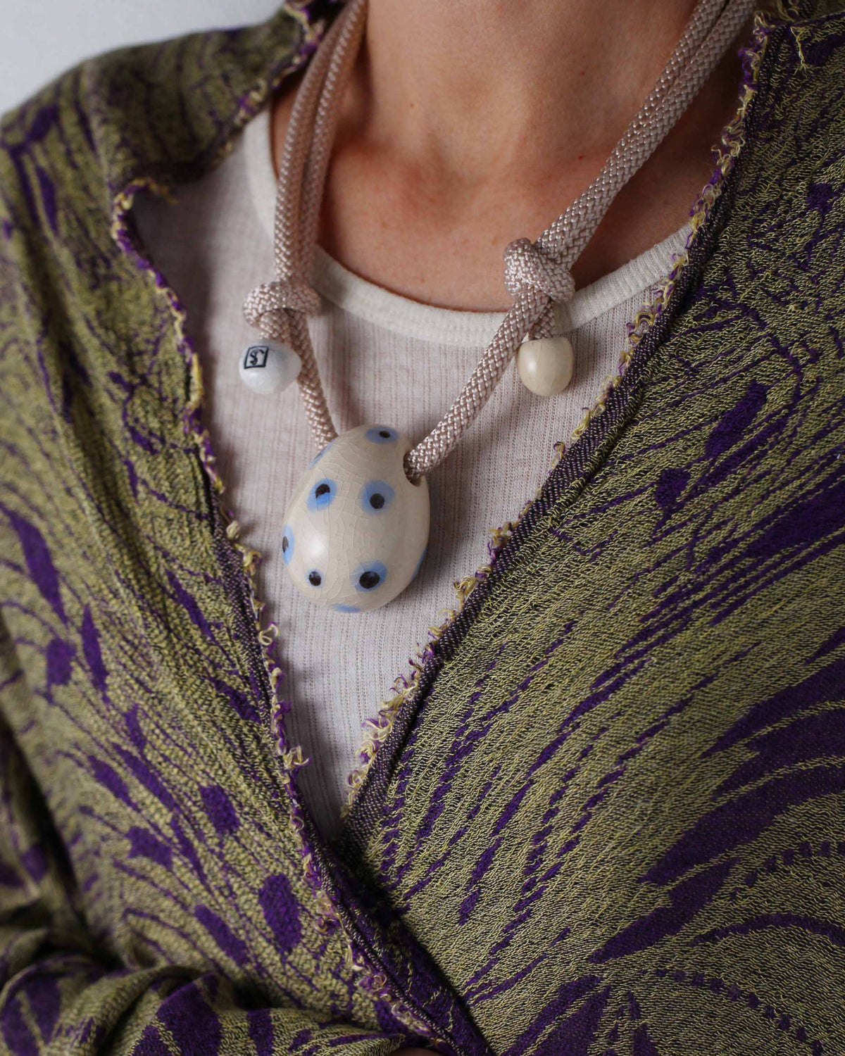 Collana Uovo Esotico – modella con giacca verde e viola