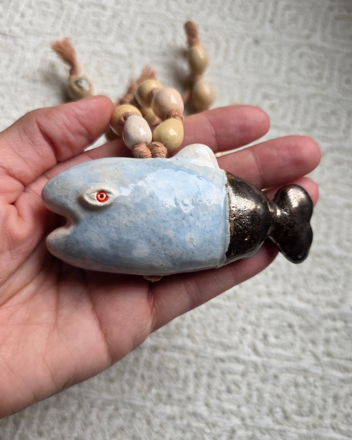 Collana Pesce Azzurro – il pesce azzurro sul palmo della mano, per la scala, con la bocca aperta e la coda scura dal riflesso metallico