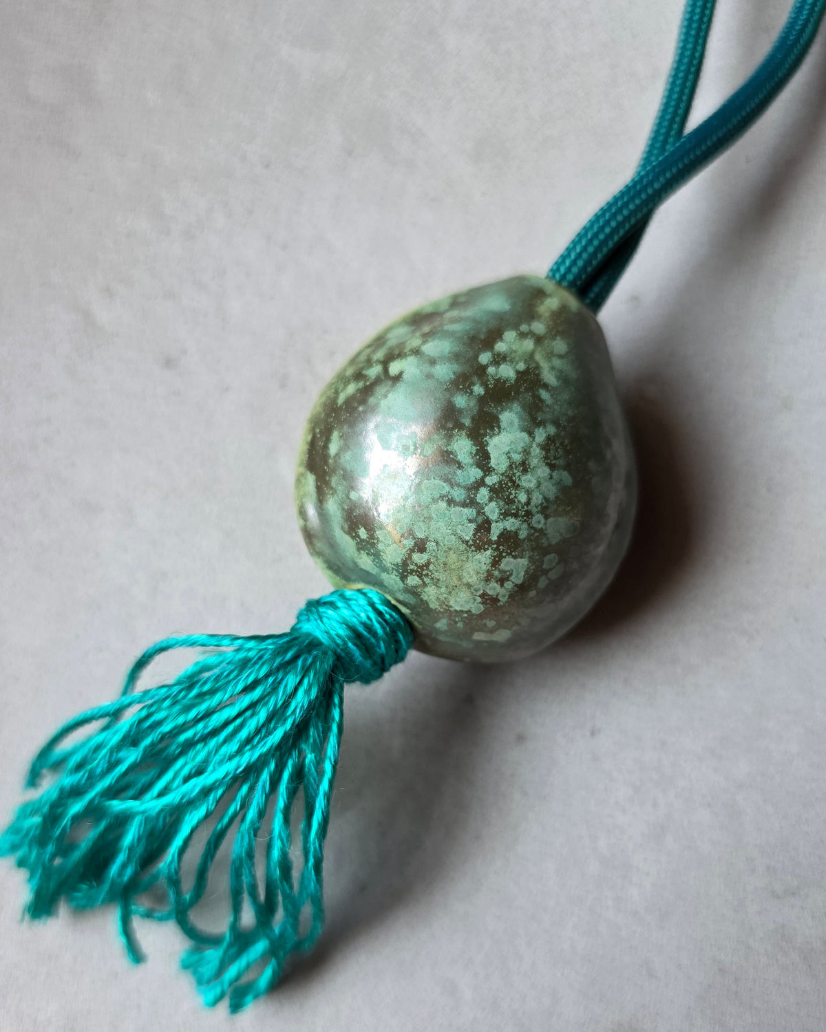 Collana Sacro Om – Turchese – la collana intera sul piano grigio