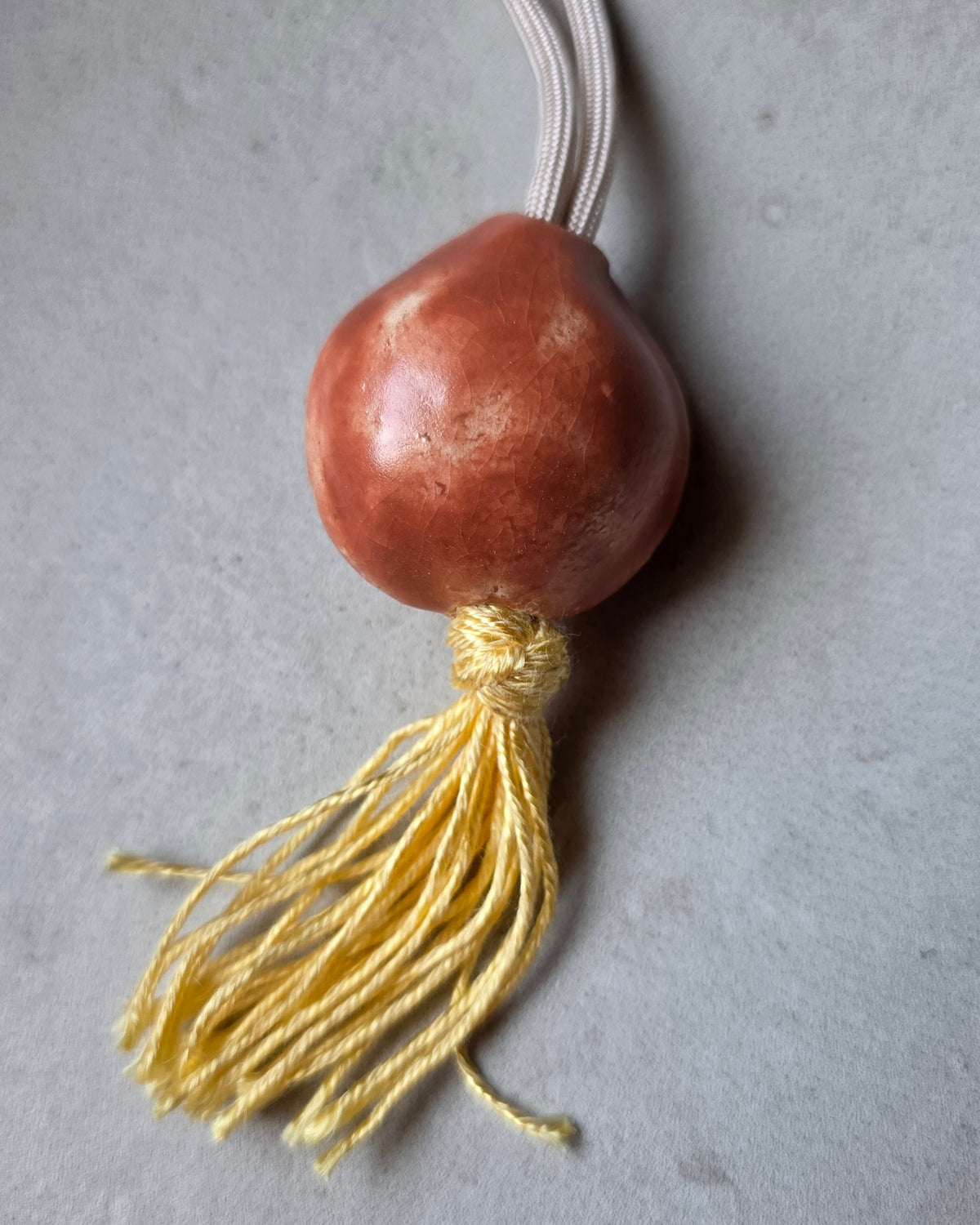 Collana Sacro Om – Terracotta – la collana intera sul piano grigio