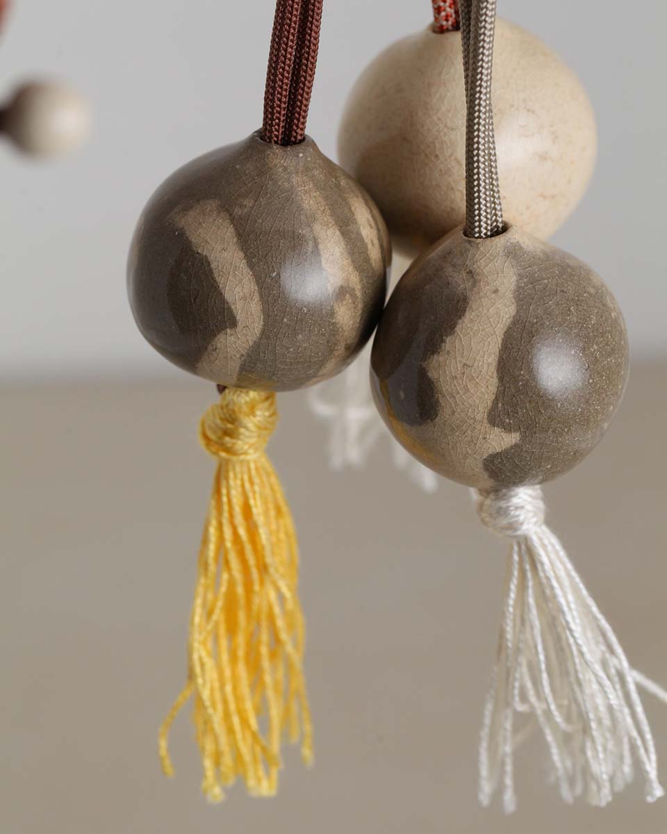 La collana in ceramica perla Nomade, color avorio e sabbia con nappina gialla