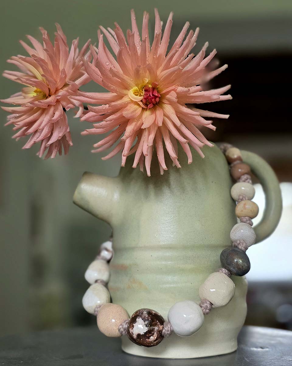 Chiacchiere tra oggetti belli, una collana in ceramica, una teiera fatta a mano e delle splendide dalie