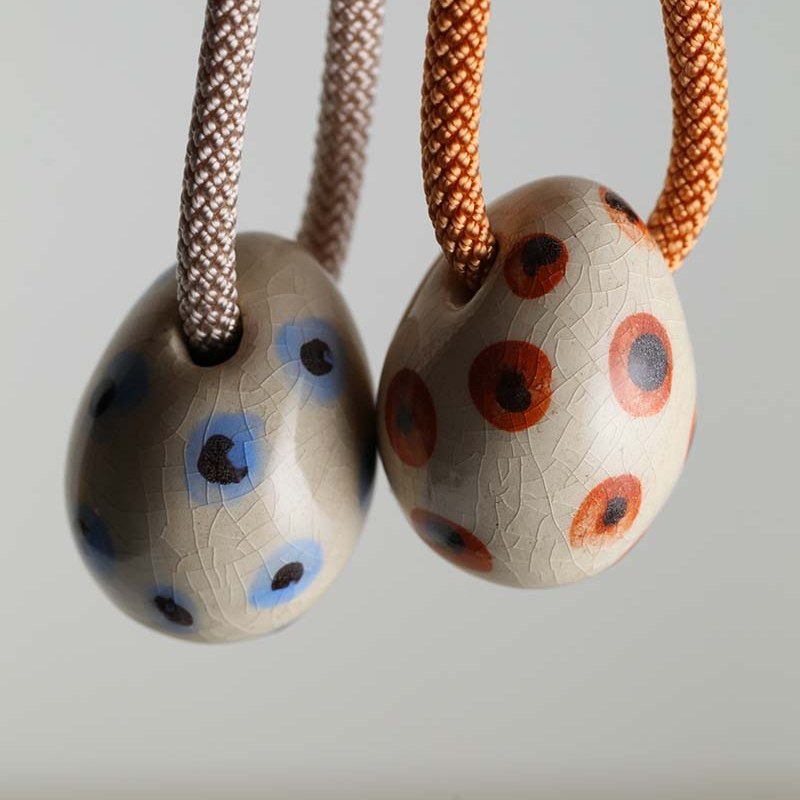 Due uova in ceramica a pois azzurri e arancioni appese a cordini tortora e arancione